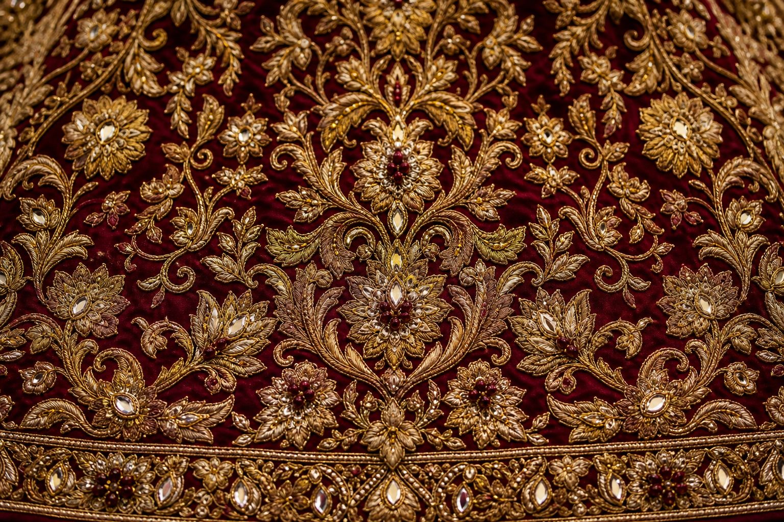 Close up of dense gold zardozi embroidery worked over deep burgundy silk