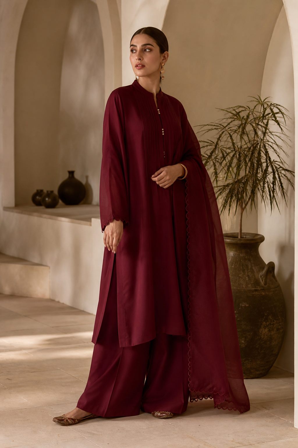 Contemporary burgundy kurta with palazzo trousers styled in an arched boutique interior