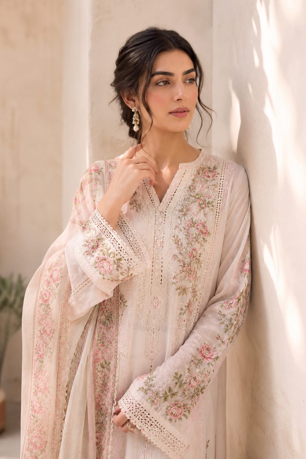 Woman in a pastel embroidered lawn suit with floral thread work, standing in soft daylight